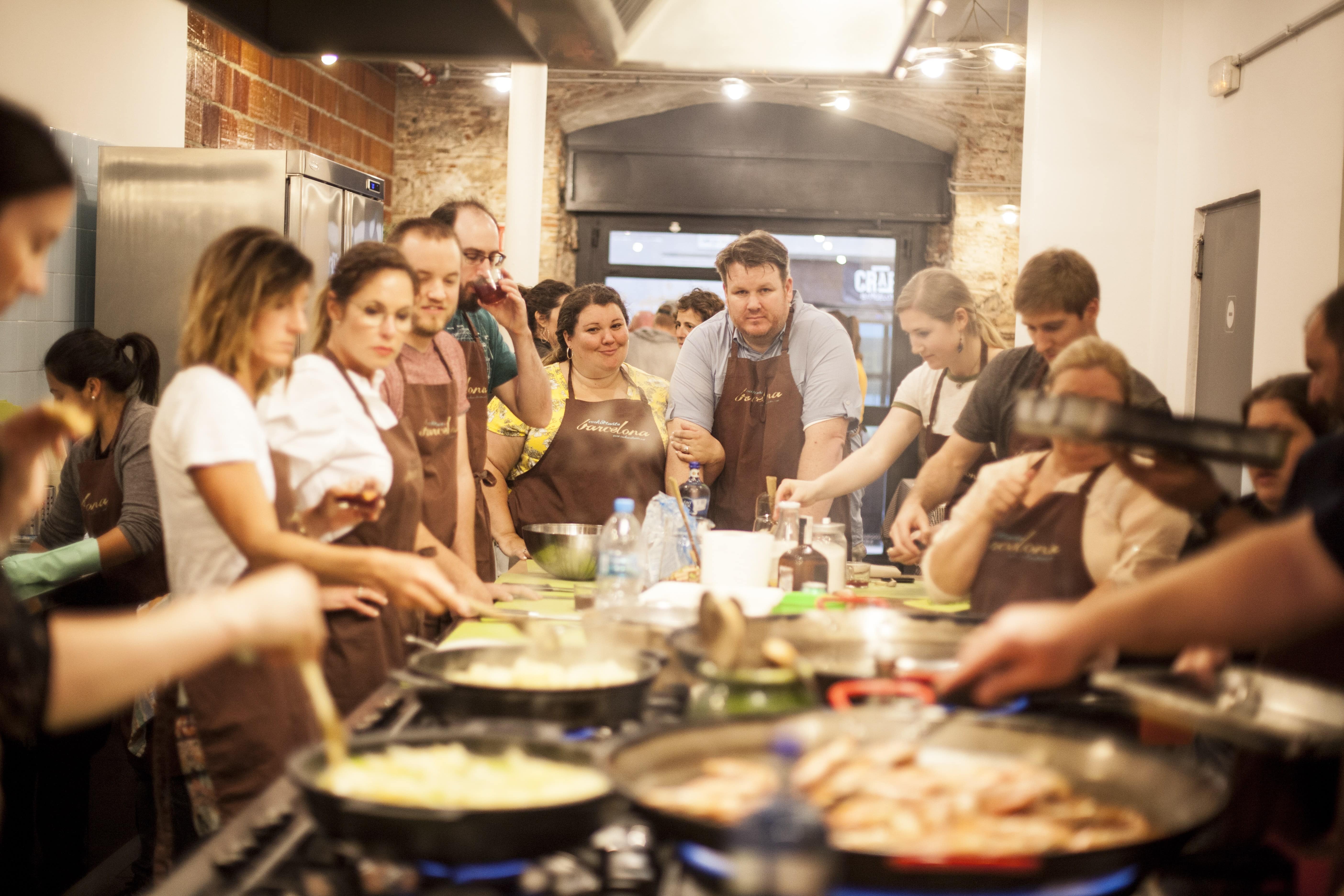 Cooking class with multiple participants preparing food in commercial kitchen